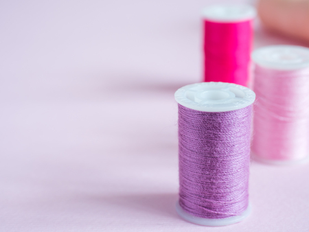 Colorful sewing buttons and thread on a pink backgroundの写真素材