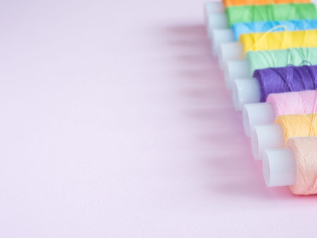 Colorful sewing buttons and thread on a pink background
