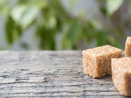 Brown cane sugar on wooden background. Green tree with leaves.の写真素材