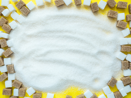 Cubes of white and brown sugar on yellow background.の写真素材