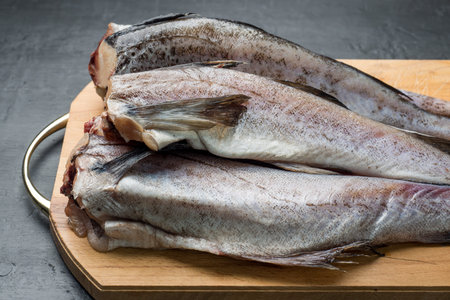 Slave raw Fish on wooden cutting Board on dark background.