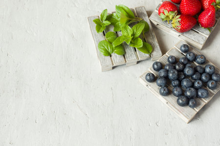 Fresh berries strawberries blueberries mint on a wooden stand, grey background with Copy space for...