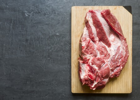 A piece of red raw beef meat on wooden cutting Board Dark background. Copy spaceの写真素材