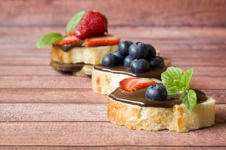 Toast bread with chocolate paste and strawberries blueberries mint on the table. Copy spaceの写真素材