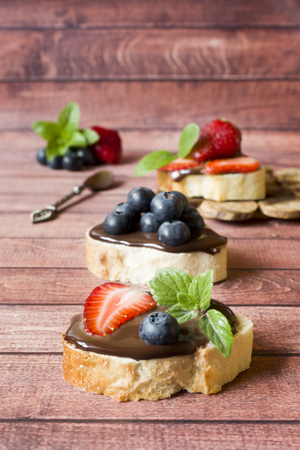 Toast bread with chocolate paste and strawberries blueberries mint on the table. Copy spaceの写真素材