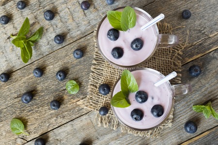 Blueberry yogurt in glass cups with fresh blueberries and mint on a wooden rustic table.の写真素材