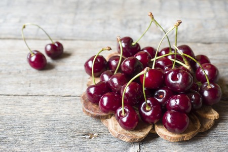 Juicy ripe cherries with twigs on wooden stand on rustic background.の写真素材