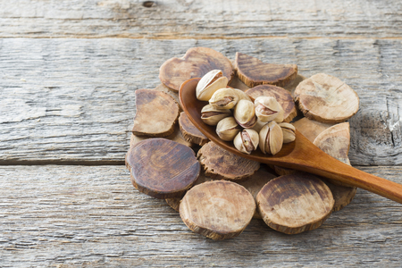 Delicious salted pistachios in a wooden spoon stand.の写真素材