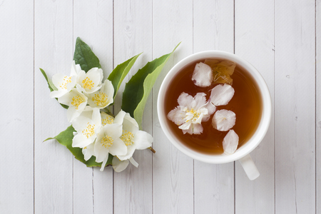 Mug of herbal tea with petals of Jasmine flowers on a light background.の写真素材