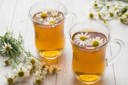 Cup of tea and chamomile flowers on wooden background.の写真素材