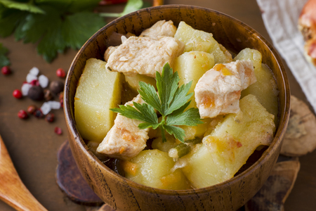 Potatoes stewed with chicken and vegetables in a wooden bowlの写真素材