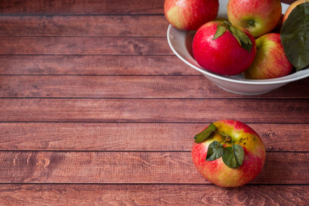 Fresh red apples with green leaves on a Dark wooden background