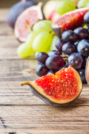 Still life of fresh autumn fruit. Grapes black and green, figs and leaves on a wooden table with copy spaceの写真素材