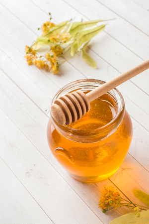 Glass jar of honey, Linden flowers on wooden background.の写真素材