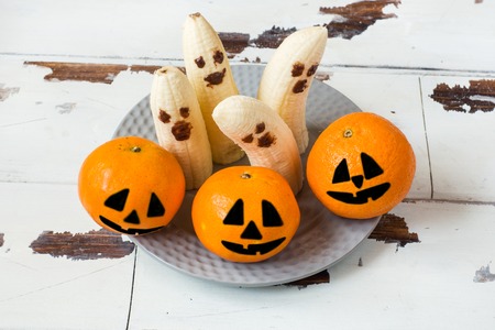 Painted funny faces on tangerines and bananas for Halloween.の写真素材
