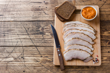 Pieces of smoked boiled pork on a wooden rustic Board with bread, sauces and spices on a wooden...