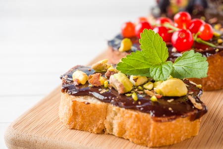Sandwiches with chocolate paste, pistachio nuts and fresh berries on a wooden serving Boardの写真素材