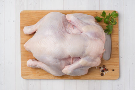 Fresh raw chicken on cutting board and spices for cooking.