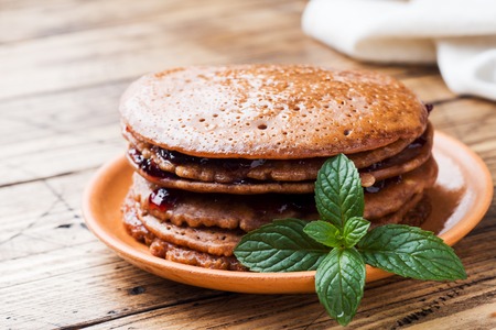 Chocolate pancakes with berry jam and mint for Breakfast on wooden background.の写真素材