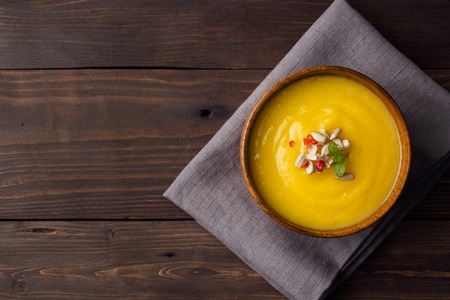 Pumpkin soup mashed with spices in wooden bowls on dark boardsの写真素材