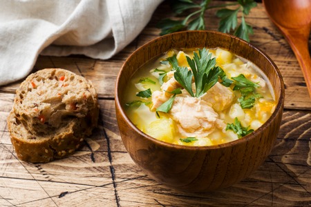 Fish soup in a wooden bowl with fresh herbsの写真素材