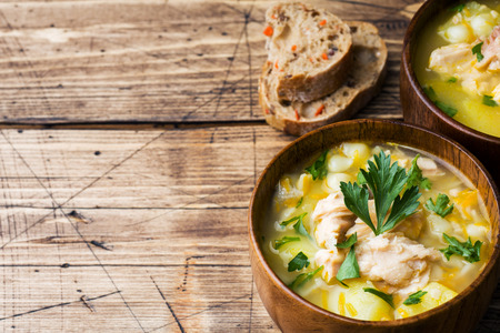 Fish soup in a wooden bowl with fresh herbsの写真素材