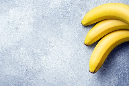 Branch of three bananas on a textured background, copy spaceの写真素材
