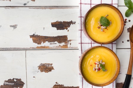 Pumpkin soup mashed with spices in wooden bowls on light boardsの写真素材