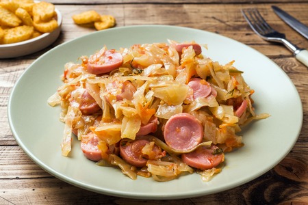 Stewed cabbage with sausages in a plate on the table. Selective focusの写真素材