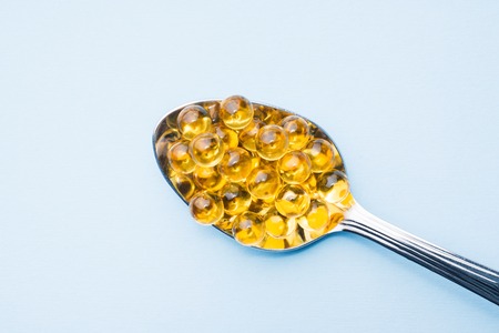 Fish oil capsules with omega 3 and vitamin D blue texture, healthy diet concept, selective focusの写真素材