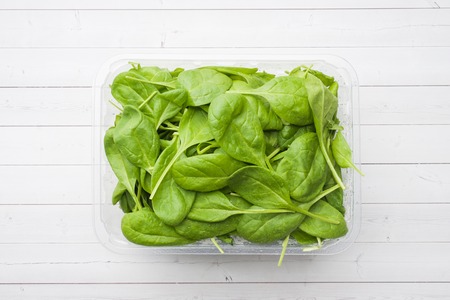 Fresh spinach leaves in a plate on a light tableの写真素材