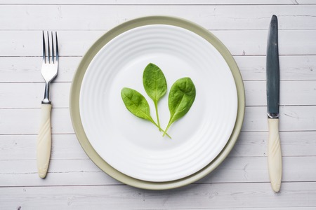 Fresh spinach leaves in a plate on a light tableの写真素材