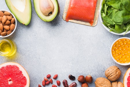Healthy food antioxidant products: fish and avocado, nuts and fish oil, grapefruit spinach and oil on a gray concrete background. copy space.の写真素材