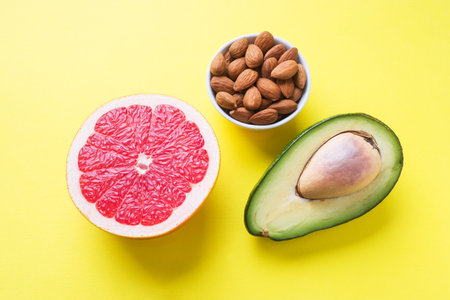 concept of healthy food. Grapefruit, avocado and almonds on a yellow background