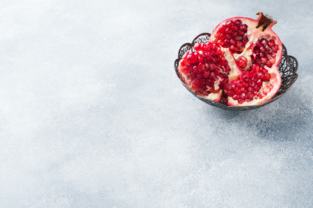 Ripe pomegranate fruit in a vintage plate on a gray textured background Copy space.の写真素材