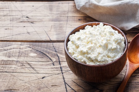 Homemade cottage cheese in a wooden bowl on old wooden tableの写真素材