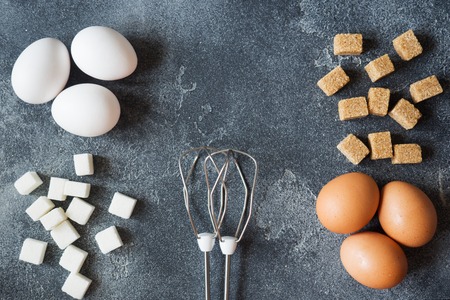concept of home cooking, eggs and sugar with a whisk on a dark table. Selective focusの写真素材
