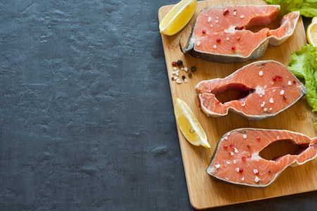 Steak raw red fish with lemon and spices dark background with copy spaceの写真素材