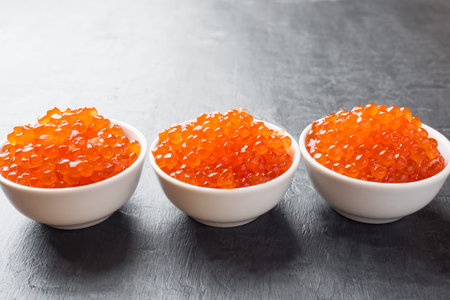 red salmon caviar in a plate on a dark table