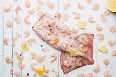 Raw carcass of squid and shrimp with spices and lemon is ready for cooking on the tableの写真素材