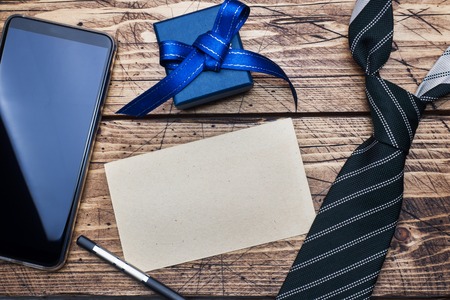Father's Day Concept. Striped tie, gift box and phone and space for text on wooden tableの写真素材