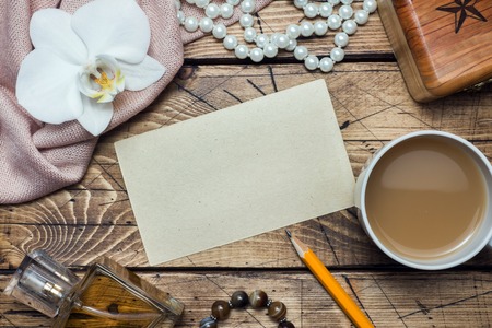 Orchid flower and accessories, cup of coffee a form for text on a wooden table. Concept romance mood. Copy space and flat lay.の写真素材