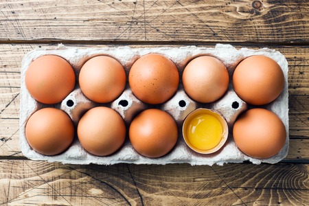 Brown raw eggs in factory packaging on rustic wooden backgroundの写真素材