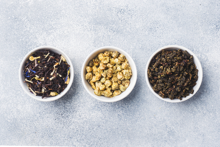 Variety of dry tea leaves and flowers in bowl on grey backgroundの写真素材