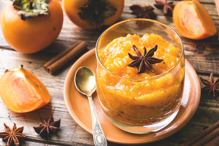 Persimmon fruit smoothie with cinnamon and anise stars, wooden table.の写真素材