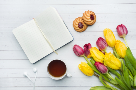 Overhead view of a bouquet of tulips and notebook and a Cup of coffee. copy space. Flat lay, top view.の写真素材