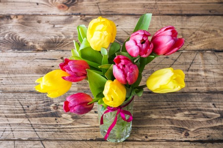 Bouquet of yellow and pink tulips on a wooden backgroundの写真素材