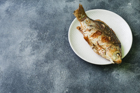 Baked carp fish on a plate. dark background. Copy space