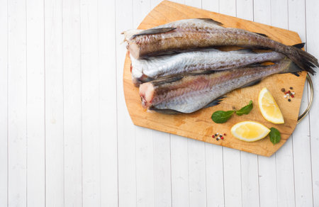 Raw fresh Pollock fish on a wooden Board with lemon. Copy space