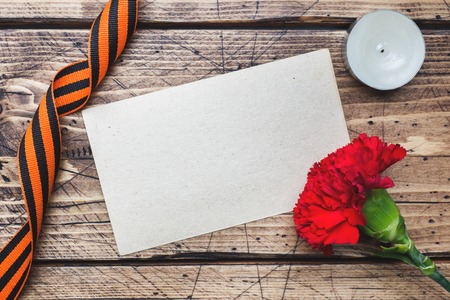 Red carnations and St. George ribbon on wooden background. Symbol may 9, victory day.の写真素材
